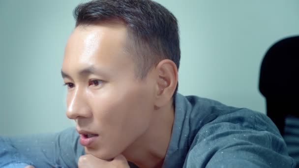 Молодой красивый азиатский мужчина, сидящий за столом в офисе — стоковое видео
