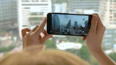 Zarif sarışın kadın telefonda bir fotoğraf yapmak. gökdelen penceresinden görünümü kadın fotoğrafları