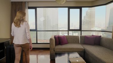 panoramik bir pencere içinde gökdelenler arka bavula kadınla