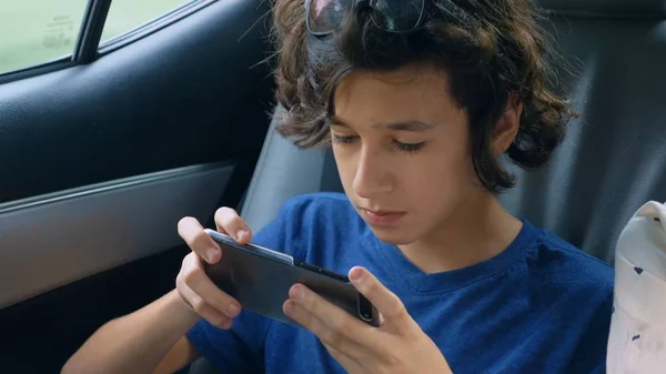 Adolescent garçon utilise téléphone tout en voyageant en voiture — Photo