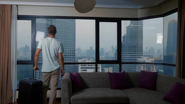 Мужчина с чемоданом на фоне небоскребов в панорамном окне — стоковое фото