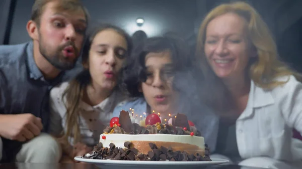 Feliz menino sorrindo soprando velas em seu bolo de aniversário. crianças rodeadas pela sua família. bolo de aniversário com velas — Fotografia de Stock