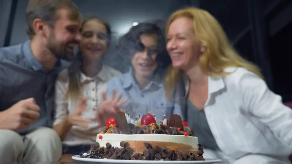 Felice ragazzo sorridente che soffia candele sulla sua torta di compleanno. bambini circondati dalla loro famiglia. torta di compleanno con candele — Foto Stock