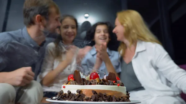 Felice ragazzo sorridente che soffia candele sulla sua torta di compleanno. bambini circondati dalla loro famiglia. torta di compleanno con candele — Foto Stock