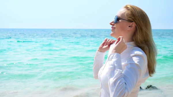 Geschäftsfrau mit Sonnenbrille am Strand. sie freut sich über das Meer und die Sonne. sie knöpft ihr Hemd auf und atmet die Meeresluft ein — Stockfoto