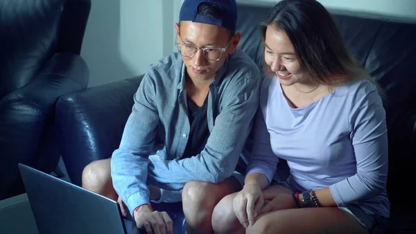 Asiático belo jovem casal sentado no sofá com tablet computador no quarto à noite . — Fotografia de Stock