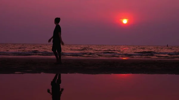 Silhueta. solitário asiático jovem caminhando pacificamente ao longo de uma praia deserta ao pôr do sol. paisagens marinhas — Fotografia de Stock