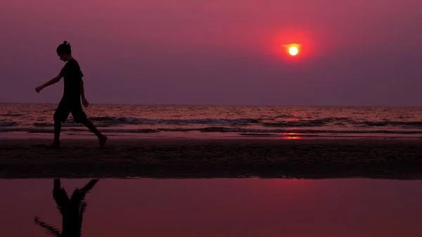 Sylwetka. samotny Azjatycka młody człowiek szedł spokojnie bezludnej plaży o zachodzie słońca. Seascape — Zdjęcie stockowe