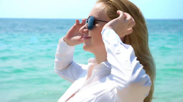 Obchodní žena v sluneční brýle na pláži. Ona se raduje v moři a slunci. Ona si rozepnul košili a dýchá v mořského vzduchu — Stock fotografie