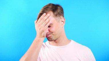 Mavi renk arka plan üzerinde genç adam. portre. duygu ve hareketleri. yakın çekim. umutsuzluk, olamaz.