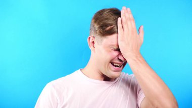 Mavi renk arka plan üzerinde genç adam. portre. duygu ve hareketleri. yakın çekim. umutsuzluk, olamaz.