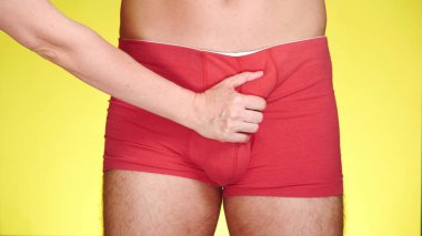 sarı bir arka plan üzerinde kırmızı boksörler adam. bir el bir adam uyluk okşadı. yakın çekim, renkli sarı arka plan