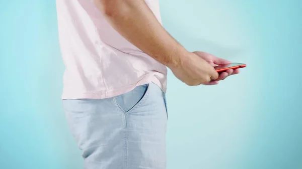Primo piano. Sfondo colorato. Un giovanotto in pantaloncini blu usa un telefono rosso — Foto Stock