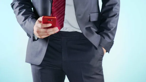 Fondo colorido. Primer plano. Muslos de un hombre. hombres de negocios en corbata roja utiliza teléfono inteligente rojo . — Foto de Stock