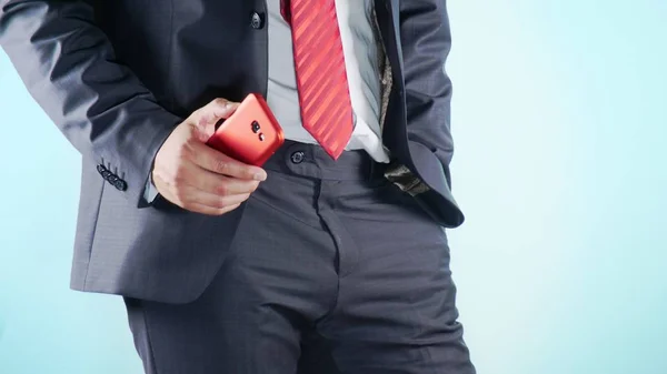 Fondo colorido. Primer plano. Muslos de un hombre. hombres de negocios en corbata roja utiliza teléfono inteligente rojo . — Foto de Stock