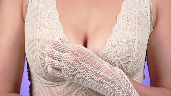 Een vrouw met een grote kist streelt haar borst met haar gehandschoende hand — Stockfoto