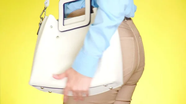 Una ragazza in jeans stretti e accessori moda, una borsa elegante bianca . — Foto Stock