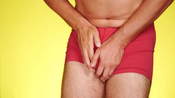The man has problems with the genitourinary system. guy in red boxers on a yellow background. — Stock Image The man has problems with the genitourinary system. guy in red boxers on a yellow background. Royalty Free Stock Photos