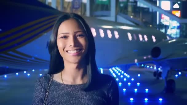 美しいアジアの女の子ニューハーフ カメラ目線と笑顔します 夕方には飛行機の背景に空港でタイのトランスジェンダーのモデル — ストック動画