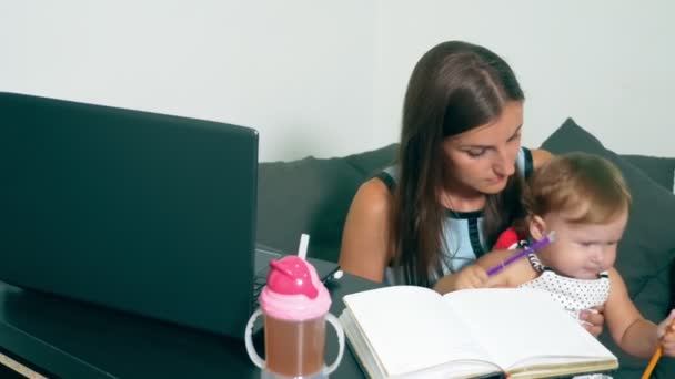 Koncepcja kobiece pracy tłumaczy. Nowoczesne macierzyństwa. Praca matki z dzieckiem przy stole. Zajęta kobieta pracuje na laptopie z dzieckiem w ramionach. — Wideo stockowe
