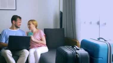 Turizm, online alışveriş turları kavramı. Romantik Çift evde seyahat için hazırlanıyor. Bir dizüstü bilgisayar ve pasaport ellerinde kanepenin üstünde oturmak. Bavulları yakın olmakla birlikte, odaklanmak