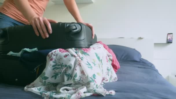 Nahaufnahme. Mädchen beiläufig packen und versuchen, einen vollen Koffer zu schließen. Konzept des lang ersehnten Urlaubs. Trennung — Stockvideo