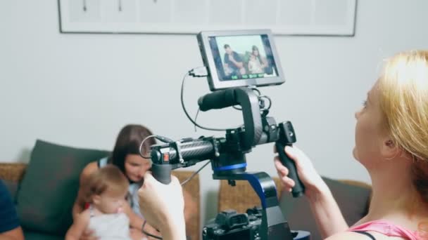 Videoinspelning processen. En operatör med en steadicam skjuter en berättelse om en familj, mamma och pappa med en liten flicka på en mysig hem soffa, som chattar sinsemellan — Stockvideo