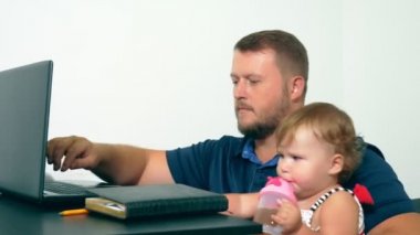 Freelancer iş kavramı. Mutlu baba çalışma vasıl ev ile bir dizüstü bilgisayar, onun kollarına bebek tutan.