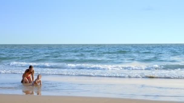 금발 아기는 모래 해변에 크롤 링, 엄마 행복 하 게 보이는 그녀 — 비디오