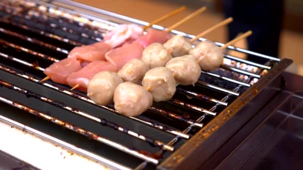 Cuisine de rue traditionnelle de Thaïlande. Cuisson de petits kebabs sur le gril la nuit à la foire de la nourriture de rue. gros plan . — Video