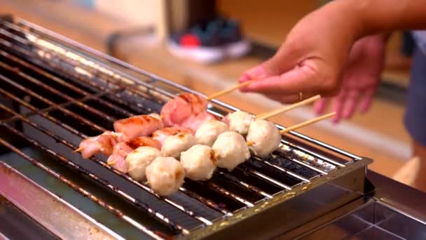 Cuisine de rue traditionnelle de Thaïlande. Cuisson de petits kebabs sur le gril la nuit à la foire de la nourriture de rue. gros plan . — Video