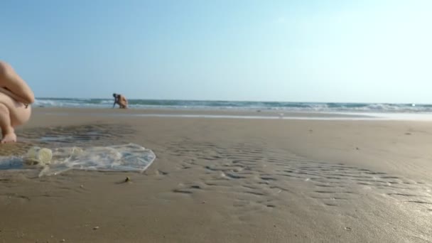 Концепція забруднення довкілля. прибережні сміття на пляжі при низькому припливі, туристи дивляться на об'єкти, що залишилися на піску після низького припливу — стокове відео