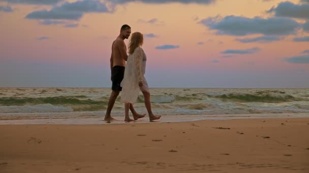 Pareja romántica, Hombre y mujer caminan por la playa al atardecer, tomados de la mano . — Vídeo de stock