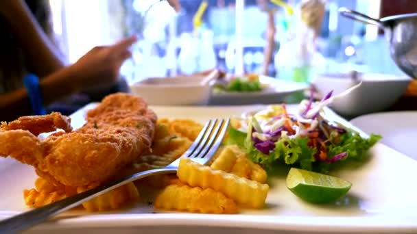 Σνίτσελ κοτόπουλο, σερβίρονται με πατάτες τηγανιτές και σαλάτα. κάποιος τρώει τηγανιτές πατάτες με ένα πιρούνι σε ένα εστιατόριο. — Αρχείο Βίντεο