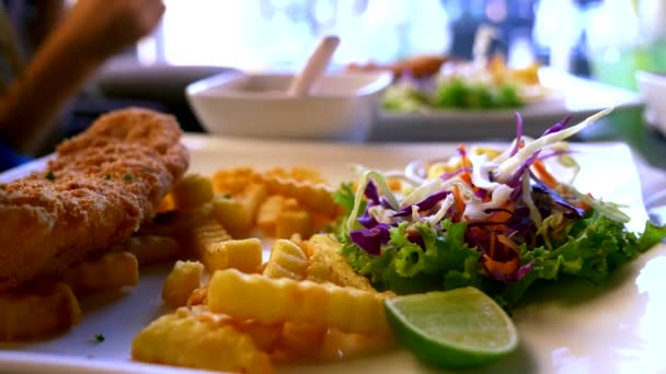 Курячий шніцель, подається з картоплею фрі та салатом. хтось їсть картоплю фрі з виделкою в ресторані . — стокове відео