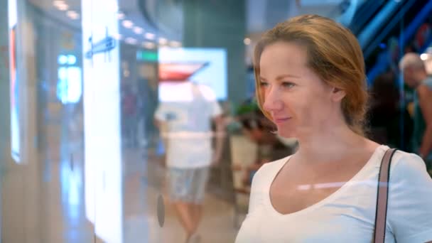 Shopping concept. young woman looking at the goods through the glass in the window — Stock Video