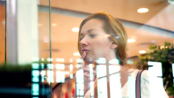 Концепція шопінгу. молода жінка дивиться на товари через склянку у вікні — стокове відео