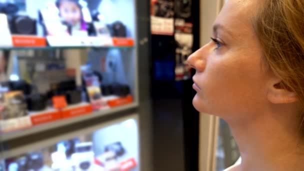 Shopping concept. young woman looking at the goods through the glass in the window — Stock Video