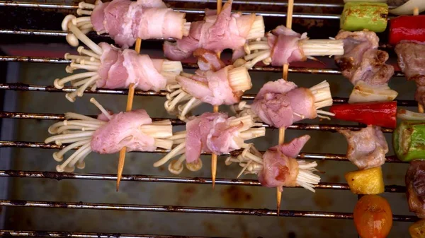 Traditionelles Streetfood aus Thailand. Nachts auf der Streetfood-Messe kleine Spieße auf dem Grill zubereiten. Nahaufnahme. — Stockfoto