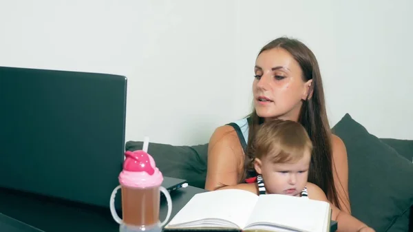 Koncepcja kobiece pracy tłumaczy. Nowoczesne macierzyństwa. Praca matki z dzieckiem przy stole. Zajęta kobieta pracuje na laptopie z dzieckiem w ramionach. — Zdjęcie stockowe