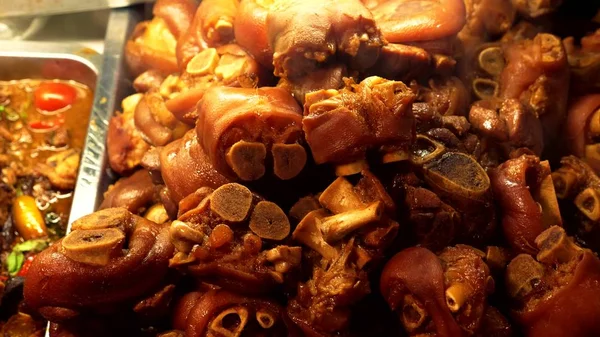 Traditionele straat voedsel van Thailand. Nationale gerechten koken 's nachts in de markt van straatvoedsel. Close-up. hete varkensvlees benen in sojasaus — Stockfoto