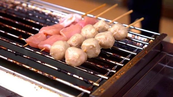 Traditionelles Streetfood aus Thailand. Nachts auf der Streetfood-Messe kleine Spieße auf dem Grill zubereiten. Nahaufnahme. — Stockfoto