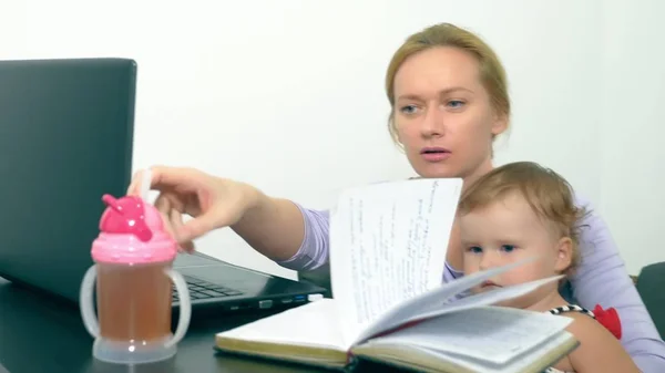 Concepto de mamá trabajadora, freelancing. madre feliz trabajando en casa con el ordenador portátil sosteniendo al bebé en sus brazos . — Foto de Stock