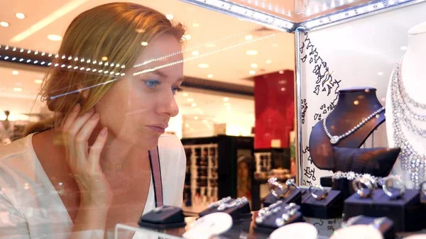 Close-up, vrouw kijkt jewelry via een showcase van glas. — Stockfoto