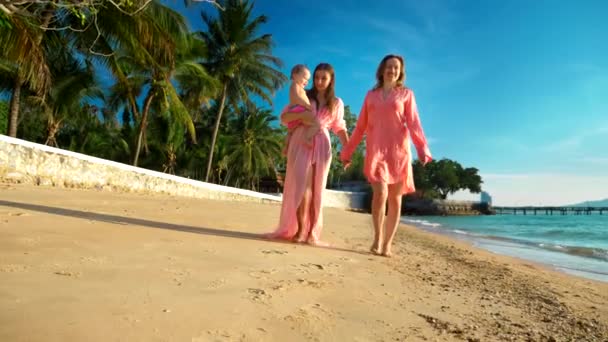 Das Konzept der seltsamen Abenteuer der Menschen. glückliches lesbisches Paar mit Babe am schönen tropischen Strand. eine der Frauen mit Schnurrbart als Symbol der Emanzipation. — Stockvideo