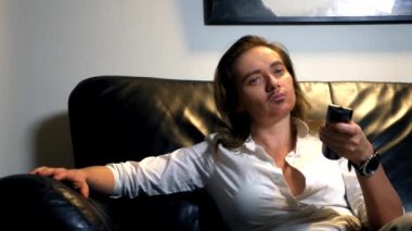 kanepede oturan ve Tv kanallarını kontrol panelinden anahtarlama yüzünde boyalı bıyıklı çift cinsiyetli bir feminist portresi