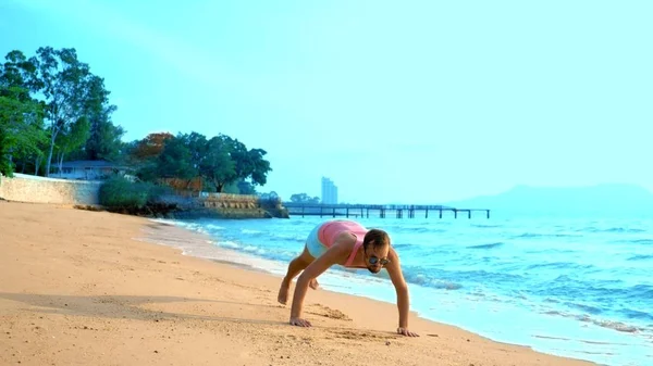 Ein verspielter gutaussehender Typ in rosa T-Shirt und blauer Shorts rennt freudig ins Meer. Freak auf dem Meer — Stockfoto
