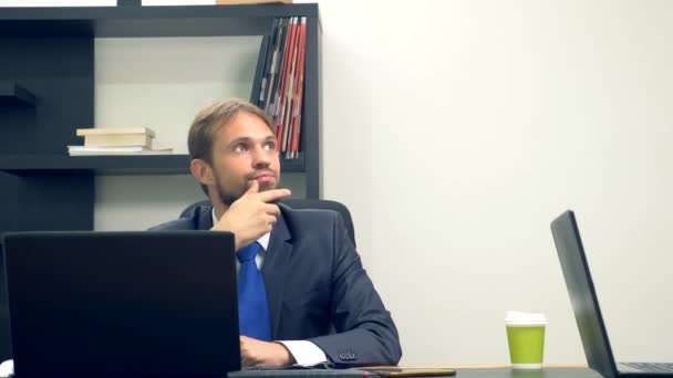 Bir takım elbiseli bir adam bir dizüstü bilgisayarda ofiste bir masada çalışır ve tek kullanımlık bardak kahve içecek. Kopyalama alanı — Stok video