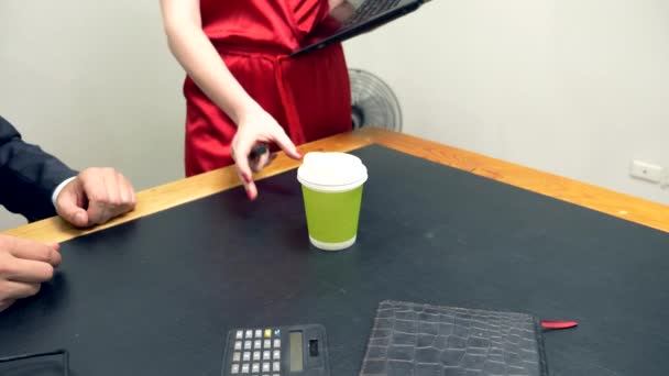 La oficina coquetea. Una mujer atractiva en un mono rojo pone su portátil en el escritorio de su prójimo . — Vídeo de stock