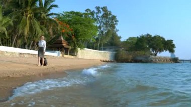 Bir bavul ile ofis giysileri iş kadın palmiye ağaçları ve lüks bir tatil zemin karşı beyaz kumlu plaj boyunca yalınayak yürüyor. serbest, uzun zamandır beklenen eğlence konsepti